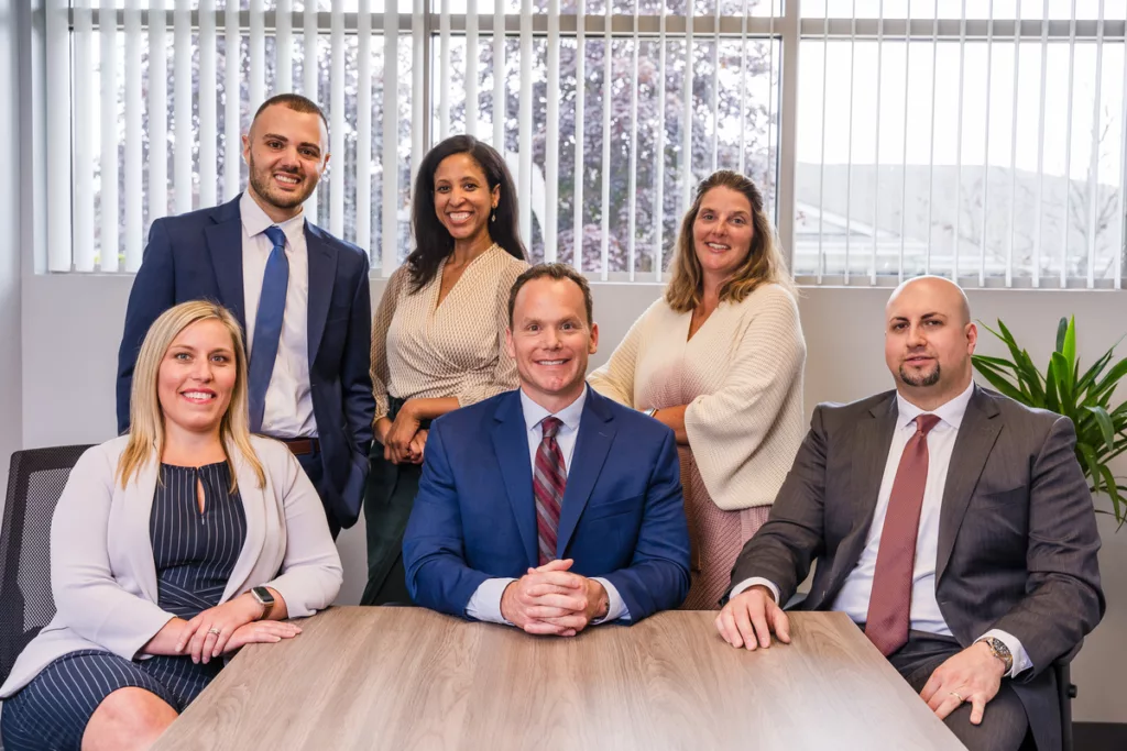 A cheerful and heartwarming photo of the 30,000 Ft Wealth Management team, all smiles and camaraderie, gathered around their conference table, reflecting their unity, professionalism, and positive work atmosphere.